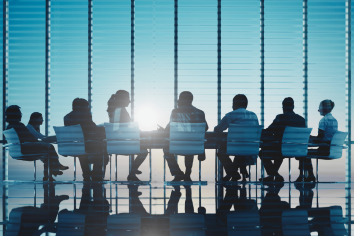 siluetes de persones entorn d'una taula de reunions