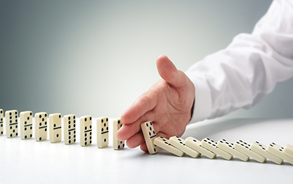a hand stopping a domino