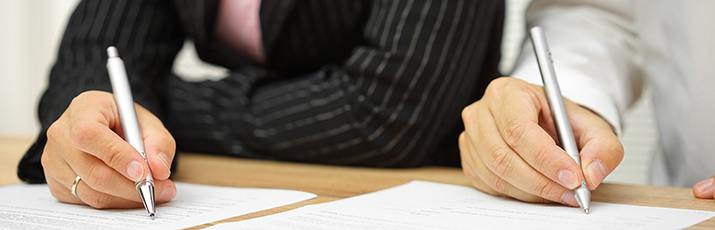 Dúas persoas asinando un protocolo de colaboración